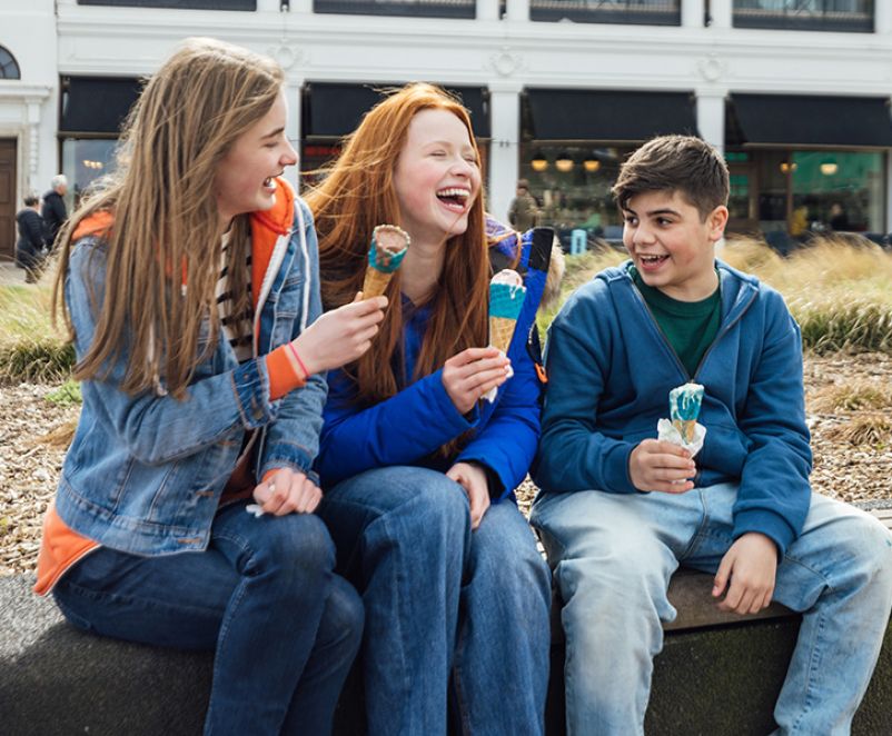 three friends enjoying ice cream on the sea front.